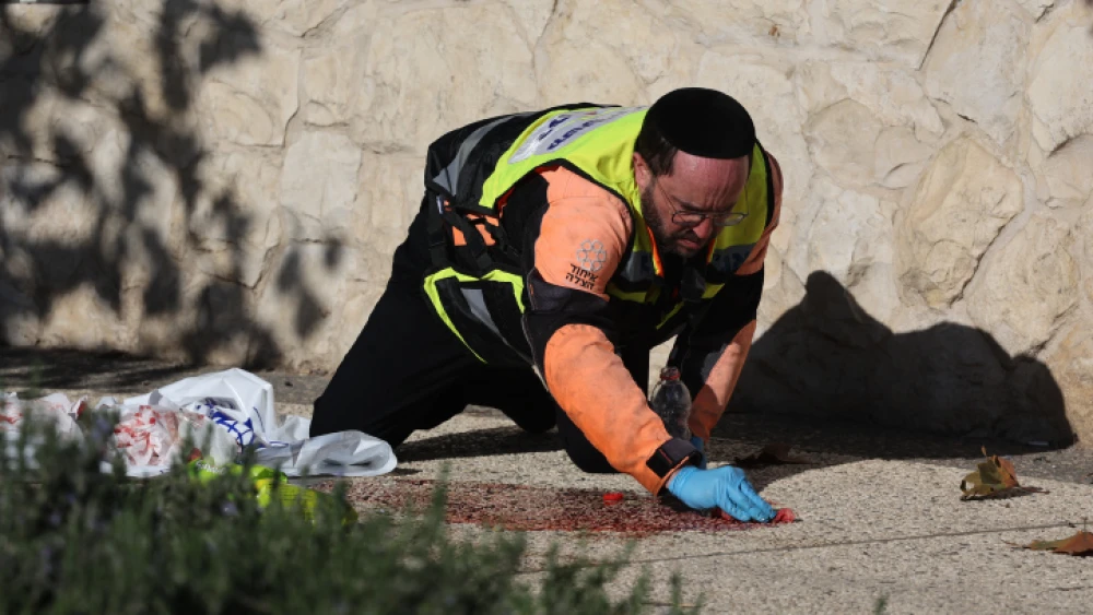 ZAKA personnel clean blood off the ground at the scene of a suspected terror attack near the entrance to Jerusalem, on Nov. 22, 2022. Two explosions at two bus stops left one person killed and at least another 13 injured. Photo by Yonatan Sindel/Flash90.