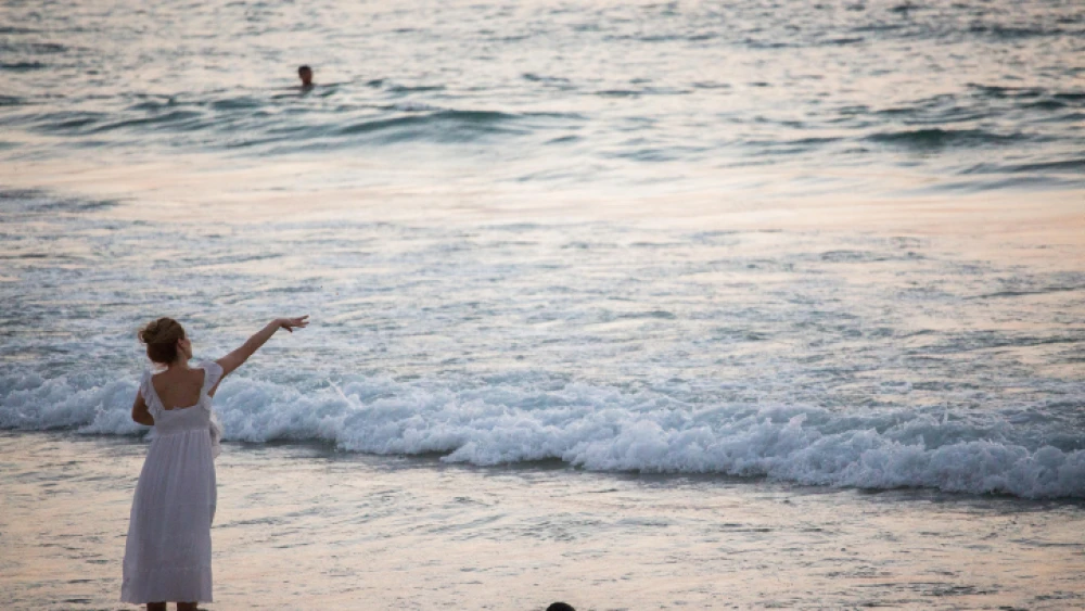 A woman performs "tashlich," a Jewish ritual performed before the eve of Rosh Hashanah, at the beach in Tel Aviv, on Sept. 10, 2018. Photo by Yonatan Sindel/Flash90.