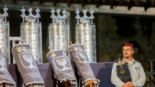 An Israeli soldier holds the Torah scroll carried by Chief IDF Rabbi Shlomo Goren in the Six-Day War, during a ceremony with 75 Torah scrolls from around the world in memory of the soldiers killed in "Operation Protective Edge" and in Israel's wars, at the Western Wall in Jerusalem, on Aug. 12, 2015. Photo by Yonatan Sindel/Flash90.