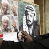 An Arab man hangs a picture of former South African leader Nelson Mandela next to a poster of former PLO chief Yasser Arafat, at a memorial service for Mandela in Jerusalem's Old City, Dec. 8, 2013. Photo by Sliman Khader/Flash90.
