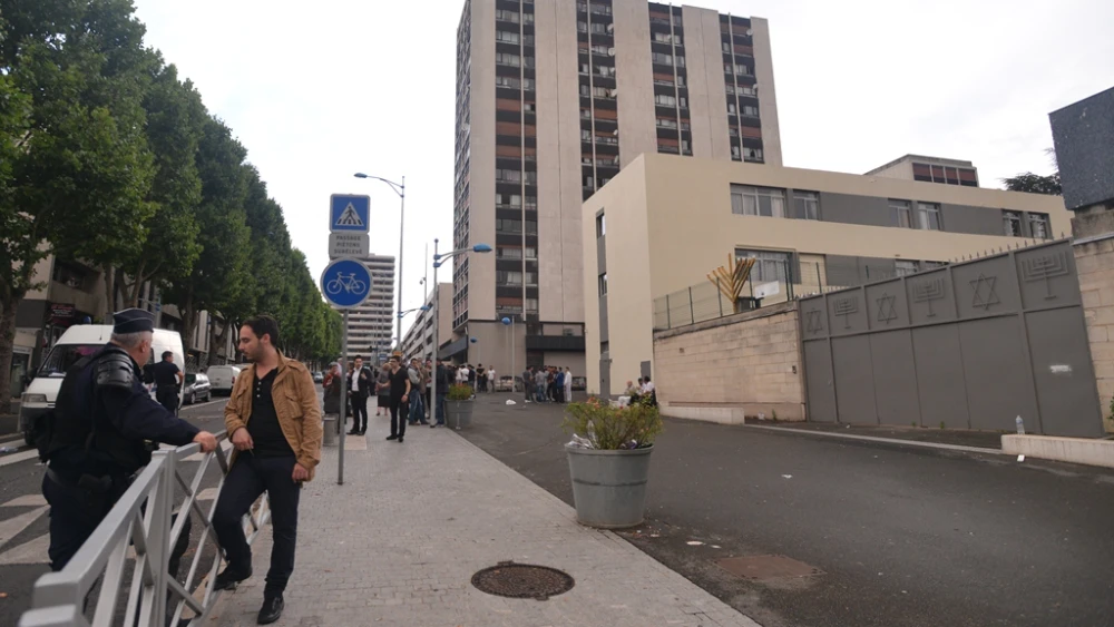 A member of the Jewish community of Sarcelles speaks with a police officer protecting the building from anti-Israel rioters on July 20, 2014. Photo by Canaan Lidor.