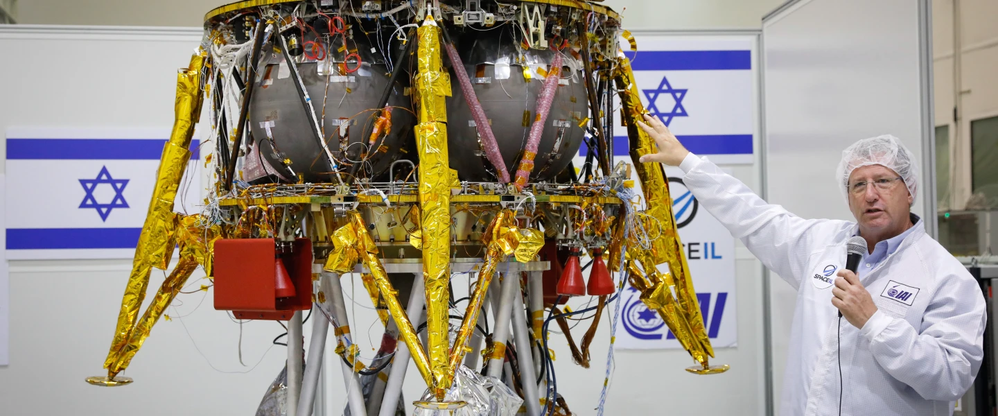 Ofer Doron, head of IAI's MBT Space Division speaks near the Israeli spacecraft of the SpaceIL team's spacecraft, during a press conference at the Israel Aerospace facility in Yahud on July 10, 2018. Photo by Flash90.