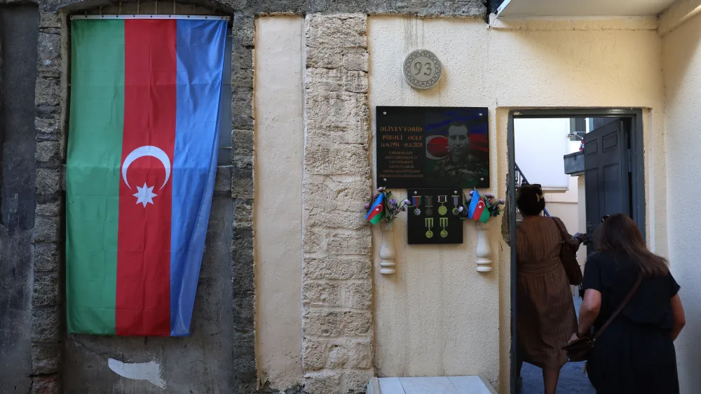 Two women enter their house past a shrine to a relative soldier killed during the 2020 war between Azerbaijan and Nagorno-Karabakh/Armenia, in the old city in Baku, Azerbaijan on Sept. 27, 2023. Photo by EMMANUEL DUNAND/AFP via Getty Images.