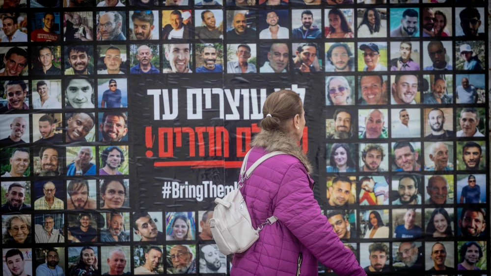 People walk next to pictures of civilians held hostage by Hamas terrorists in Gaza, in Jerusalem, Feb. 12, 2024. Photo by Chaim Goldberg/Flash90.