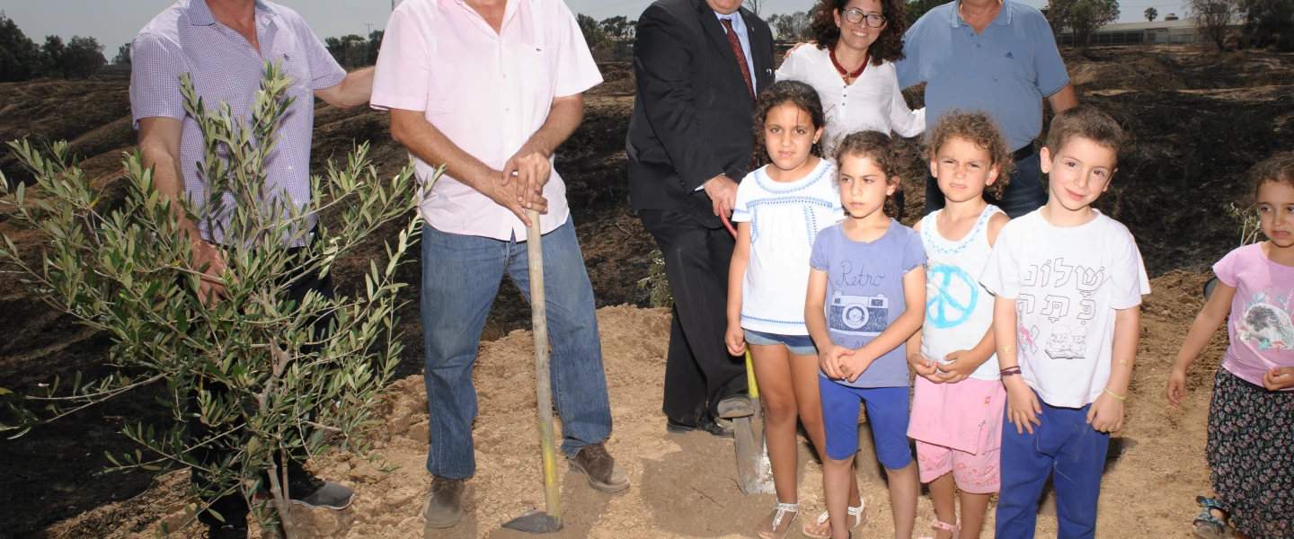 From left: Ron Werner, Mayor Gadi Yarkoni, CEO of JNF-USA Russell Robinson, Michal Uziyahu, Alon Shuster and kids in Eshkol plant an olive tree in the burnt ground where an incendiary kite from Gaza had destroyed all vegetation. Credit: Courtesy.