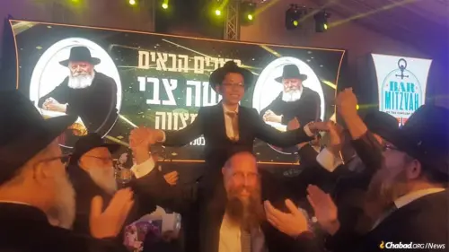 A celebratory bar mitzvah crowd dances with Moshe Holtzberg, orphaned in the Mumbai Chabad center massacre that took the lives of his parents 11 years ago this week. Credit: Chabad.org/News.