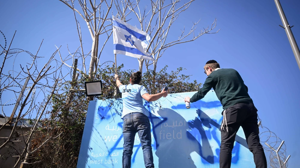 Israeli protesters, including B'tsalmo CEO Shai Glick (right), paint over the sign outside the former U.N. Relief and Works Agency for Palestine Refugees (UNRWA) office in Jerusalem's Ma'alot Dafna neighborhood, Jan. 30, 2025. Photo by Aron Leib Abrams/Flash90.