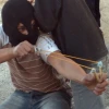 Click photo to download. Caption: In Silwan, an older balaclava-clad child with a slingshot fires off a stone at the cops, as cameras in front of him captured his “heroic” pose. Credit: B. Davidson.