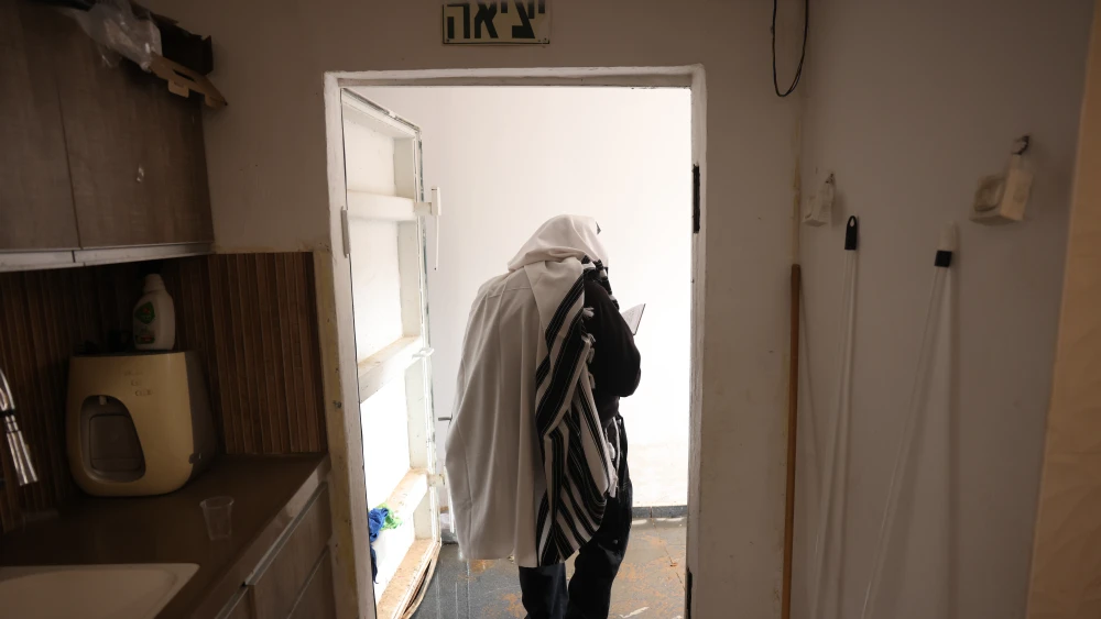 A religious Jewish man wearing a prayer shawl heads to a bomb shelter in the northern Israeli city of Safed during a siren warning of incoming missile fire amid the war with Iran and Hezbollah, March 2026. Photo by David Cohen/Flash90.