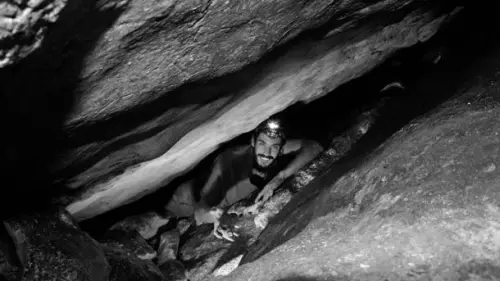 Extricating an oil lamp from a crevice between boulders. Photo by B. Zissu/ Te’omim Cave Archaeological Project.