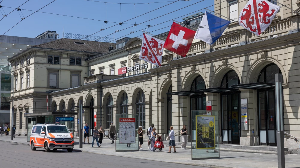 Commuters walk past a police vehicle parked in front of the central train station, where a man wounded three people with a bladed weapon in Winterthur, near Zurich on May 29, 2026. (Photo by ARND WIEGMANN / AFP via Getty Images)