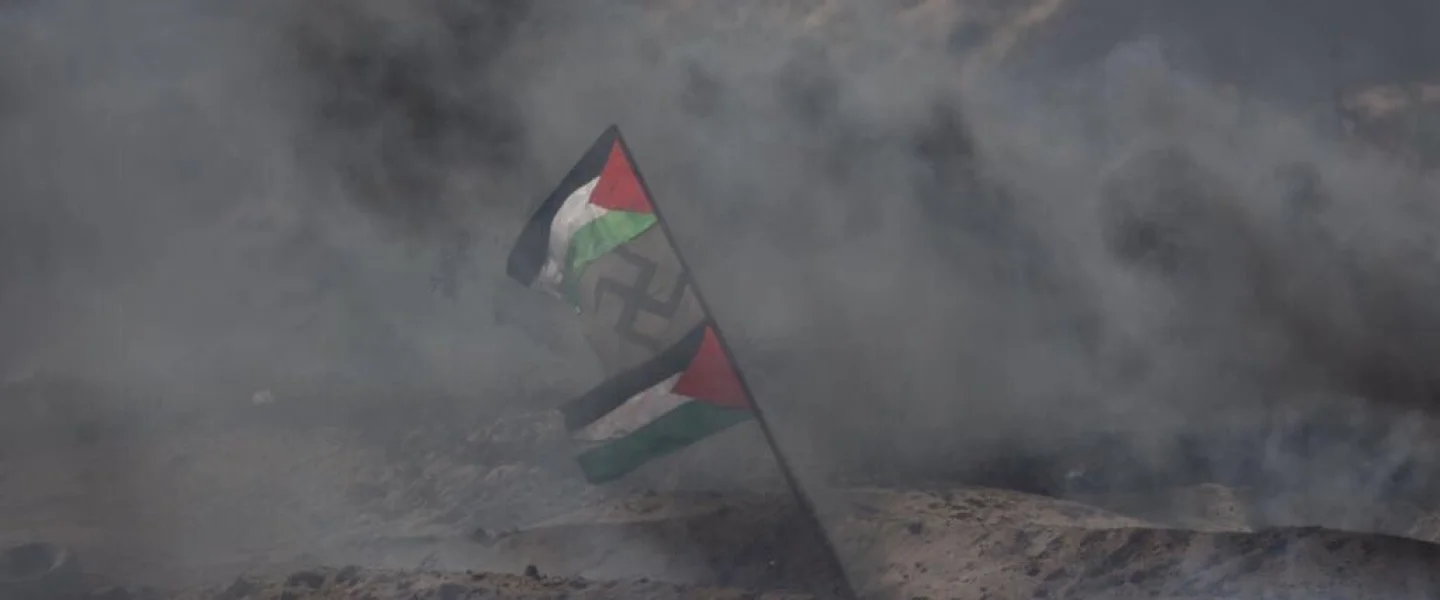 Palestinians display a flag with a swastika in the middle during Gaza border protests in April 2018. Credit: IDF via Twitter.