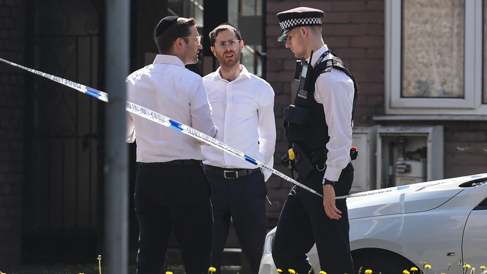 A policeman (R) walks past local residents near the site where a fire broke out at a supermarket in the Golders Green neighborhood in north London on May 27, 2026. Photo by Toby Shepheard / AFP via Getty Images.