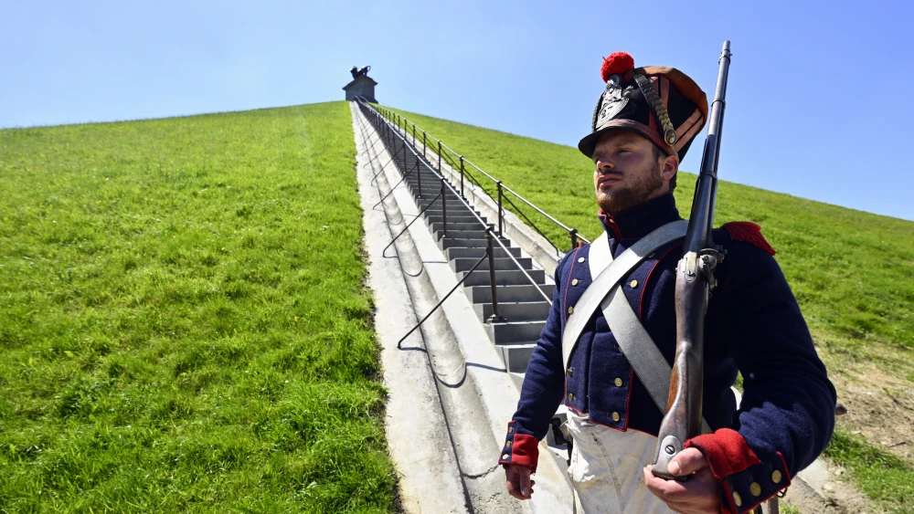 A man dressed as a member of the French Imperial Guard stands guard at the foot of the Waterloo Lion's Mound monument in Braine-l'Alleud, Belgium, on May 22, 2026. Photo by Eric Lalmand/Belga/AFP via Getty Images.