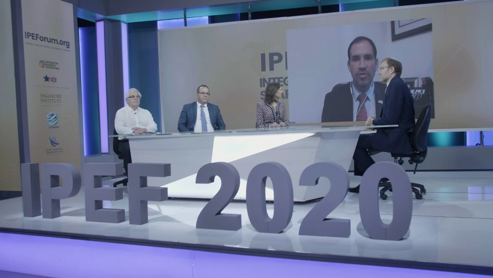 Professor Glenn Yago of the Milken Innovation Center, Ayoub Kara of the Economic Peace Center, businesswoman Tally Zingher, and on the screen in back, Aryeh Lightstone of the U.S. embassy in Israel. Photo by Amitai Eisenberg.