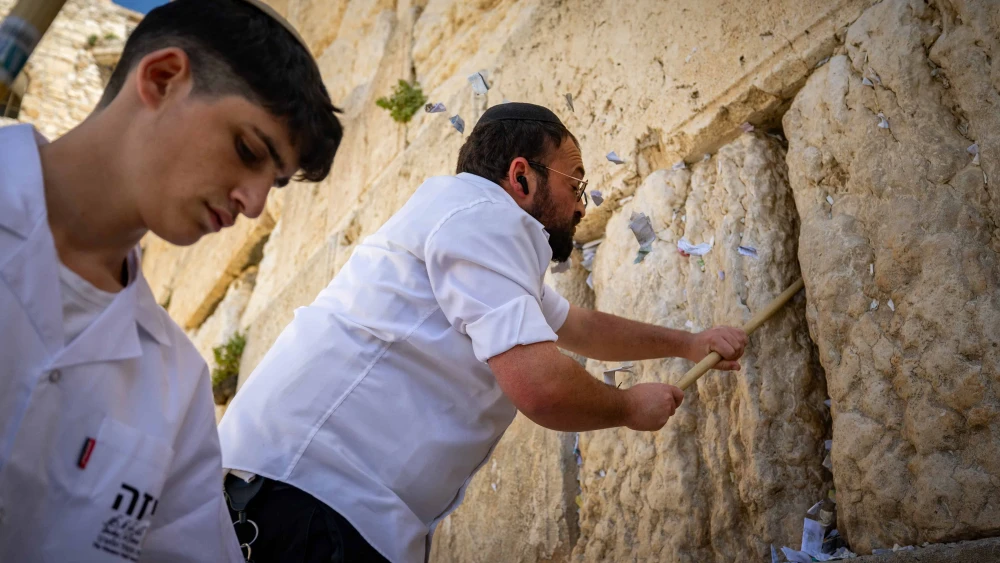 Workers remove handwritten notes placed between the ancient stones of the Western Wall in the Old City of Jerusalem, April 2, 2025. Photo by Yonatan Sindel/Flash90.