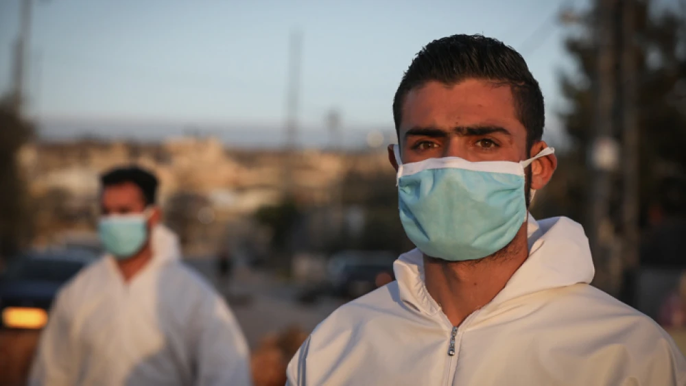 Palestinian medical employees disinfect Palestinian workers returning from their jobs in Israel at the entrance to the West Bank village of Hussan on March 29, 2020. Photo by Nati Shohat/Flash90.