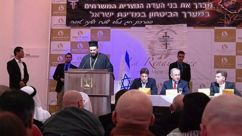 Click photo to download. Caption: Father Gabriel Naddaf addresses Christian IDF soldiers in December 2014, with Israeli Prime Minister Benjamin Netanyahu (sitting at table, in center) in attendance. Credit: Maor X via Wikimedia Commons.