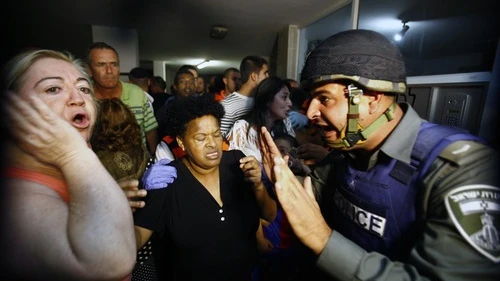 An Israeli border policeman tries to comfort residents in an apartment building after a Grad missile fired by Palestinian terrorists inside the Gaza strip exploded outside their building in Ashdod, Israel, on Oct. 29, 2011. Credit: EPA/EDI ISRAEL.