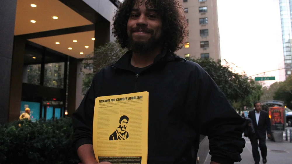 A demonstrator holds a flier bearing the portrait of George Ibrahim Abdallah outside the mission of France to the United Nations in New York on Oct. 16, 2017. Photo by Joe Catron/Flickr.