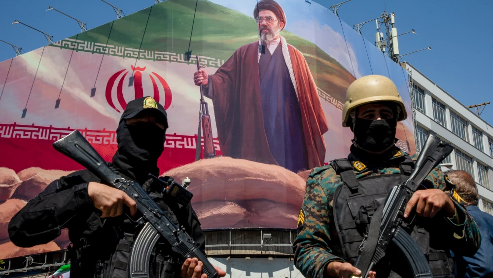 Members of the Iranian security forces stand guard under a portrait of Supreme Leader Mojtaba Khamenei, during a memorial to mark the 40th day since his father, Ali Ayatollah Khamenei, was killed in a joint U.S.-Israel strike, Tehran, April 9, 2026. Photo by Majid Saeedi/Getty Images.