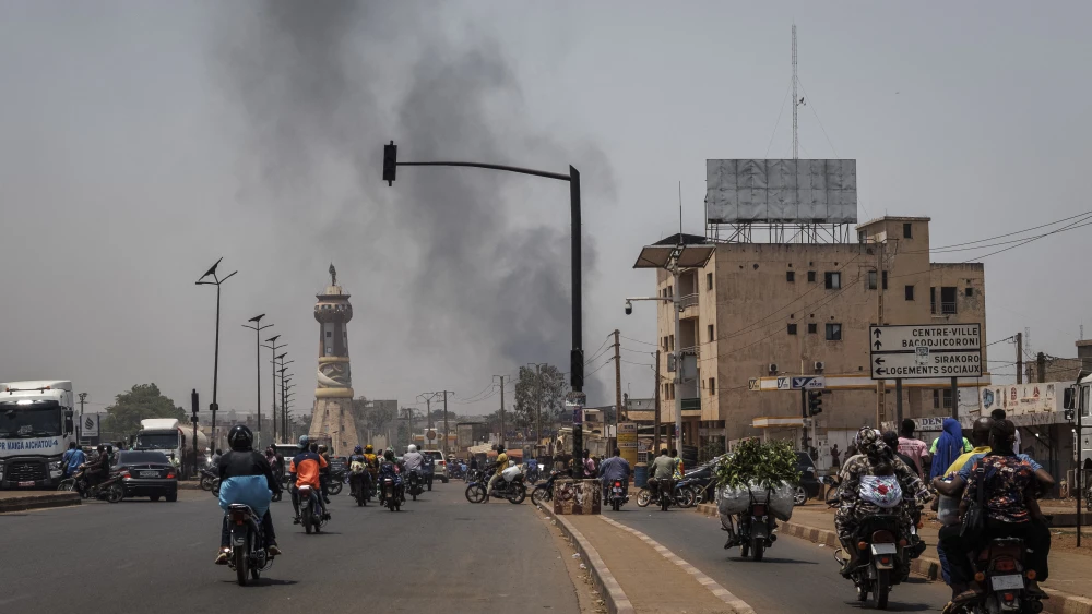 Smoke rises above buildings as traffic passes the Africa Tower monument in Bamako, the capital of Mali, on April 26, 2026. Shock attacks the day before, synchronized by Tuareg rebels of the Azawad Liberation Front coalition and the Group for the Support of Islam and Muslims, targeted several areas in the country. Photo by AFP via Getty Images.