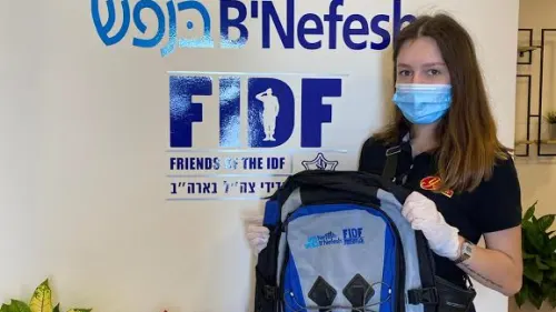 A lone soldier and new recruit in the Israel Defense Forces holds up an official backpack, April 2020. Credit: Courtesy.
