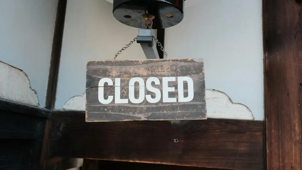 Wooden "Closed" sign hanging above a door. Credit: Huu Huynh/Pexels.