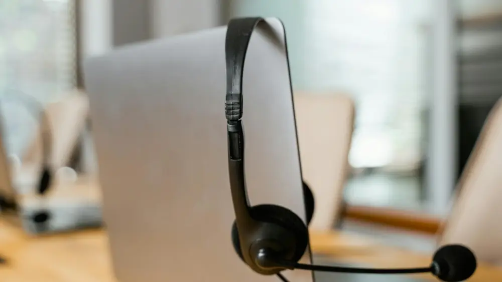 A headset resting on an open laptop screen. Credit: Mart Production/Pexels.