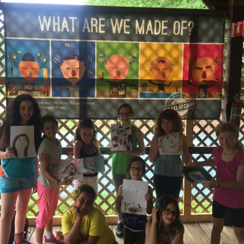 Campers show off their Hanoch Piven-inspired portraits in front of their Israel @ Camp banner. Credit: iCenter for Israel Education.