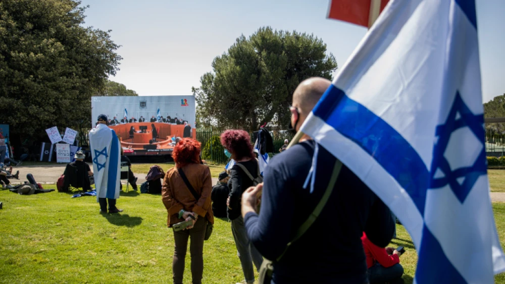 Israelis watch a Supreme Court session on petitions filed against the proposed government, outside the Knesset in Jerusalem, on April 3, 2020. Photo by Yonatan Sindel/Flash90.