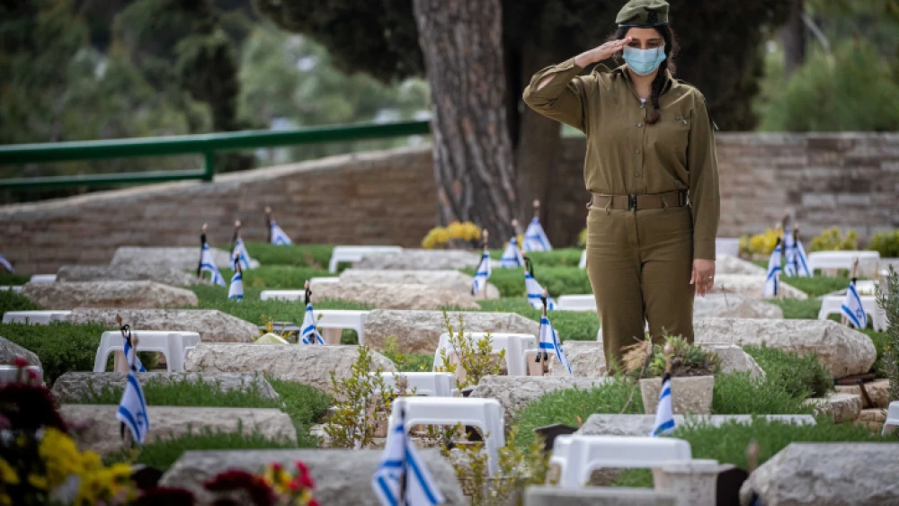 An IDF soldier participates in the annual ceremony, ahead of Memorial Day, of laying Israeli flags on the graves of fallen soldiers at the Mount Herzl military cemetery in Jerusalem, April 11, 2021. Photo by Yonatan Sindel/Flash90.
