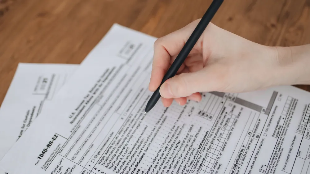 A person filling out IRS tax forms. Credit: Polina Tankilevitch/Pexels.