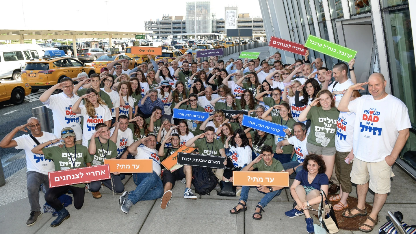 A group of soon-to-be volunteers in the Israel Defense Forces gather outside of John F. Kennedy Airport in New York and salute their future. Credit: Shahar Azram.