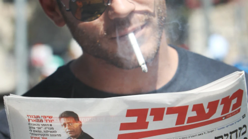 Israelis read about raised taxes on cigarettes and beer back on July 26, 2012. Photo by Miriam Alster/Flash90.