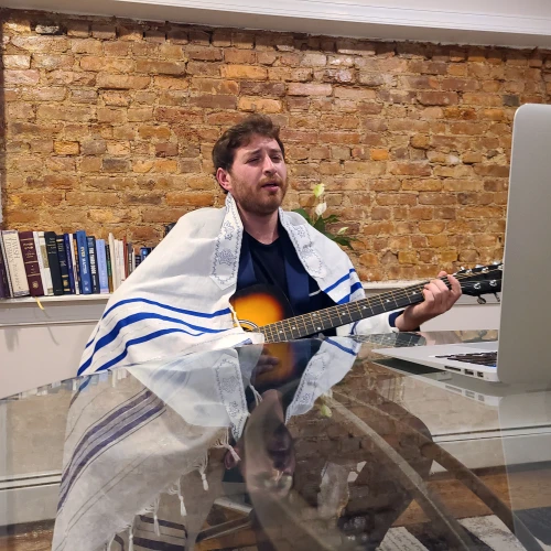 Levi Cohen at his computer as he sings melodies welcoming the onset of Shabbat. Credit: Dovid Zaklikowski.