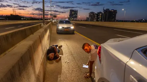 Israelis take cover by the side of a highway as a siren warns of incoming rockets, Oct. 17, 2023. Photo by Yossi Aloni/Flash90.