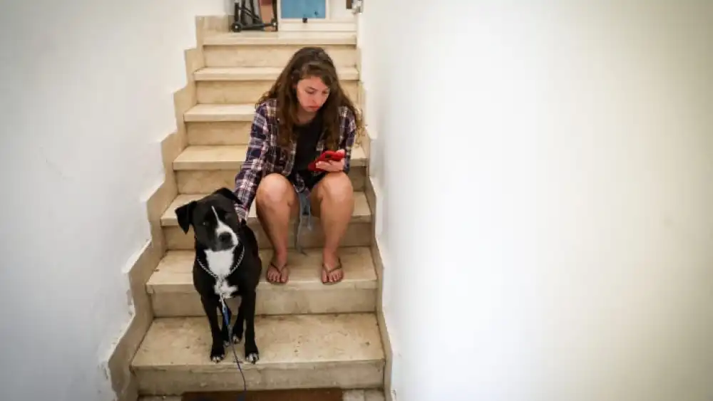 A woman and her dog takes cover in a stairway in Jerusalem as a Red Alert is sounded when a rocket barrage is fired from the Gaza Strip into Israel, Oct. 7, 2023. Photo by Noam Revkin Fenton/Flash90.
