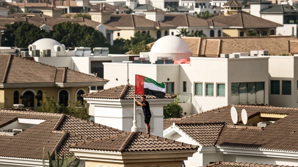A man fastens a United Arab Emirates flag to the roof of his house in Dubai on April 14, 2026, after the country’s vice president and ruler of Dubai urged residents to hoist the flag as a symbol of unity and pride. Photo by Fadel Senna/AFP via Getty Images.