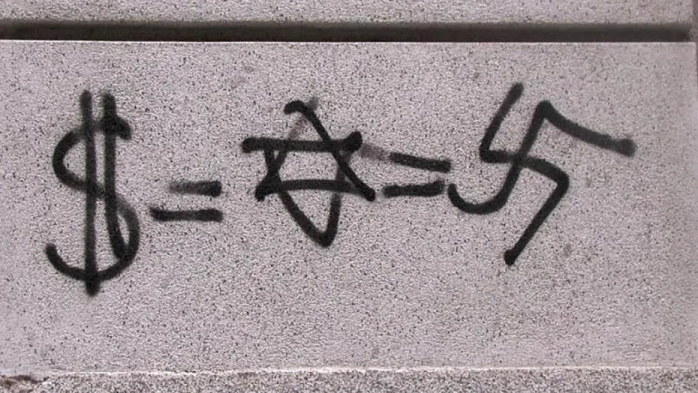 Anti-Semitic graffiti equating Judaism with Nazism and money, found in Madrid in 2003. Credit: Wikimedia Commons.