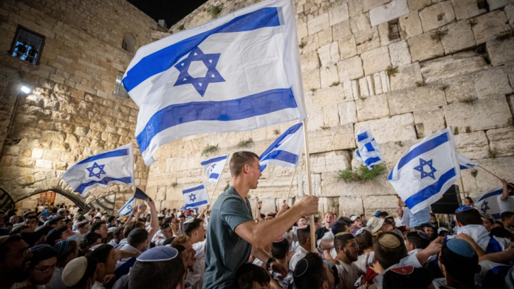 Israelis wave flags at the Western Wall in Jerusalem's Old City on the eve of Jerusalem Day, May 9, 2021. Photo by Yonatan Sindel/Flash90.