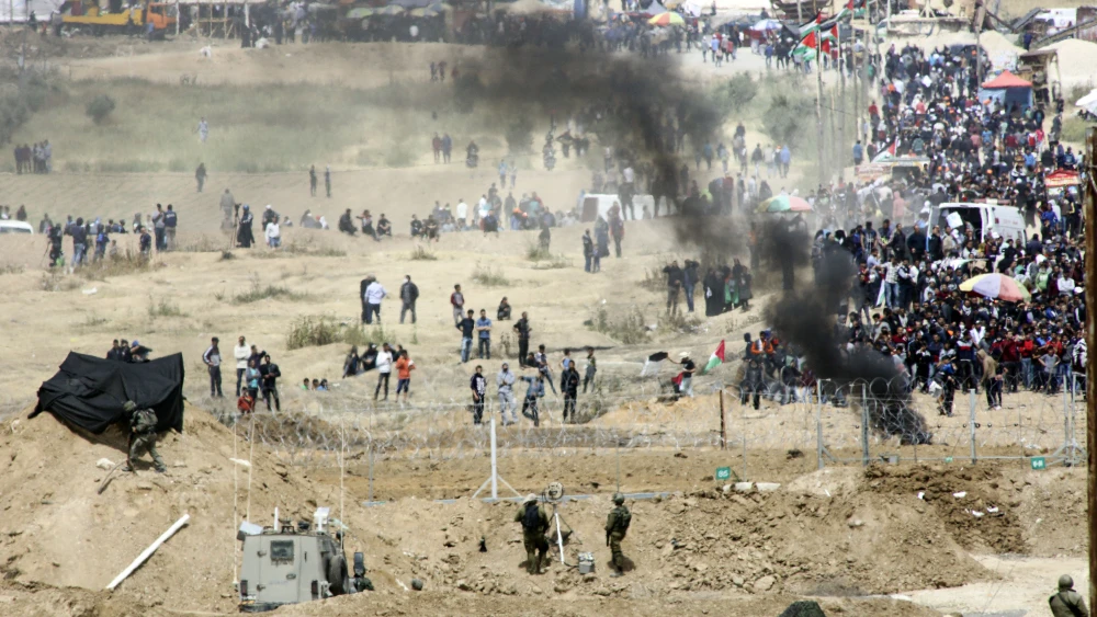 Palestinian protesters demonstrate and burn tires near the border with Israel in the Gaza Strip, as seen from the Israeli side of the border, on April 13, 2018. Credit: Sliman Khader/Flash90