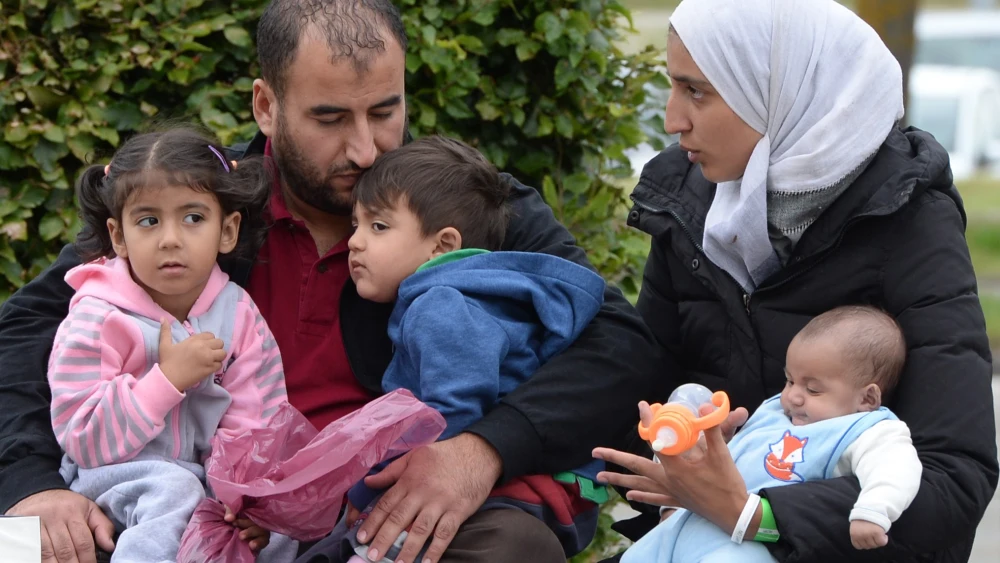 A refugee family from Syria waits in front of a exhibition hall at the Munich fairground that serves as makeshift shelter for migrants after they arrived in Germany, Sept. 07, 2015. Photo by Christof Stache/AFP via Getty Images.