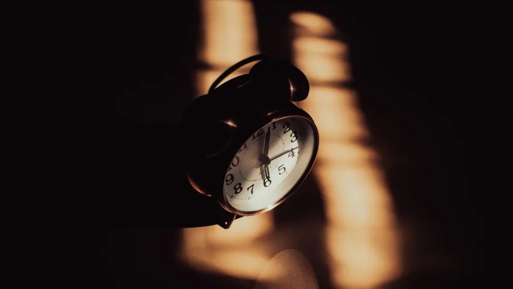 A clock sitting on a desk. Credit: Ruslan Sikunov/Pexels.
