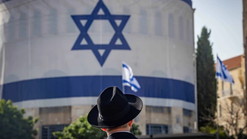 An Ultra-Orthodox Jewish man standing under a huge Israeli flag in Jerusalem, June 3, 2024. Photo by Yonatan Sindel/Flash90.