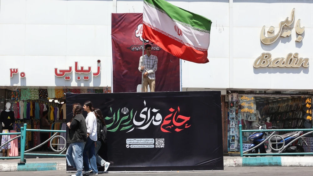 An Iranian man holds Iran's national flag at Valiasr Square in Tehran on July 16, 2026. Photo by AFP via Getty Images.