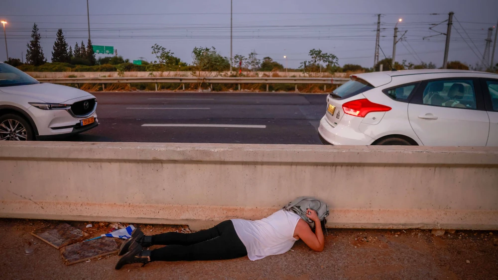 Israelis take cover on a road in central Israel as an air-raid siren warns for incoming rockets, Nov. 2, 2023. Photo by Chaim Goldberg/Flash90.