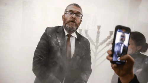 Grzegorz Braun stands next to a Hanukkah menorah after using a fire extinguisher on it inside the Polish parliament in Warsaw, Poland on Dec. 12, 2025. Photo courtecy of Rabbi Sholem Stambler.