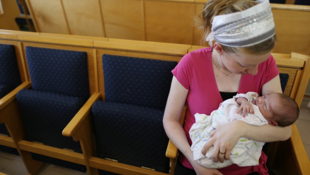 A young mother comforts her baby boy after a brit milah has been performed in a synagogue in Jerusalem on Aug. 30, 2013. Photo by Nati Shohat/Flash90.