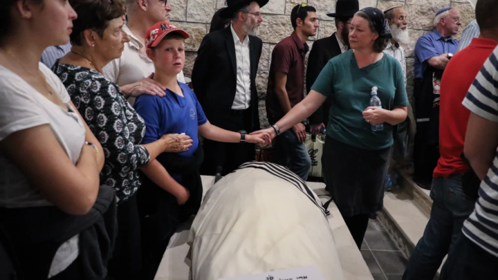 Ari Fuld's wife, Miriam, and son hold hands over his enshrouded body, wrapped in a tallit and awaiting burial at the Kfar Etzion cemetery in Judea. Photo by Gershon Elinson/Flash90.